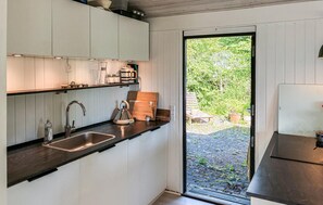 Eine moderne Küche mit Spüle, Wasserkocher und Schneidebrett aus Holz.