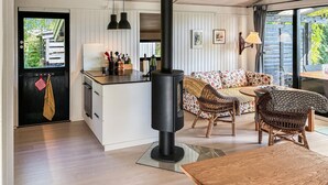 Et moderne køkken med en central ø, en indbygget træovn og et spiseområde med fletmøbler.