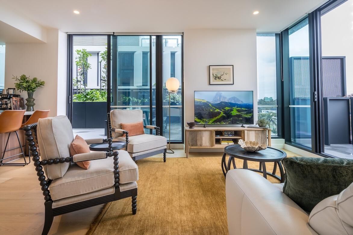 Un salon moderne comprenant un canapé, des fauteuils, une table basse et un téléviseur.