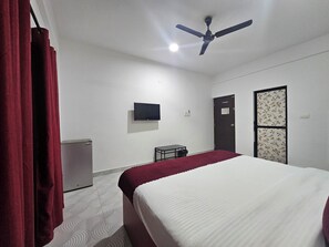 A room with a bed, a ceiling fan, a television, a desk, and a wardrobe. - Coastal Chapter, 5 minutes to Calangute Beach (Calangute)