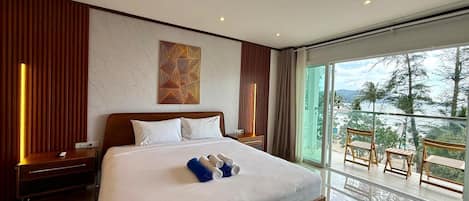 A hotel room with a large bed, a nightstand, a bedside table, a window with a view of the outdoors, and a balcony with wooden furniture.