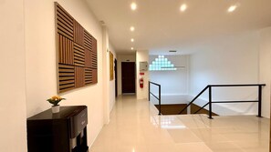 A hotel lobby with a modern design, featuring a reception desk, a staircase, and a fire extinguisher. - Patong Deluxe Double Room with Balcony and Seaview (Tambon Patong)