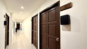 Pasillo de hotel con puertas cerradas, un extintor y un letrero con el número 301.