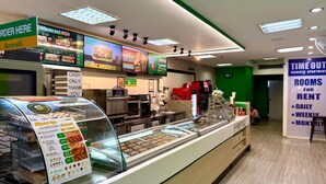Mostrador de comida con menú, aviso de pago en efectivo y reloj digital.