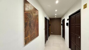 A hallway with a patterned wall, wooden doors, and a tiled floor. - Boutique 1BR Suite with Sea View, Patong (Tambon Patong)