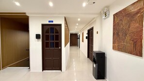 A hotel hallway with a wooden door, a water dispenser, and a patterned wall. - Boutique 1BR Suite with Sea View, Patong (Tambon Patong)