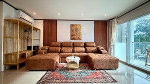 Una sala moderna con un sofá modular, otomanas, una mesa de centro redonda y un ventanal con vistas.