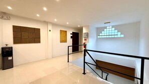 A modern interior with a water dispenser, a staircase, and a wall with geometric patterns. - Boutique 1BR Suite with Sea View, Patong (Tambon Patong)