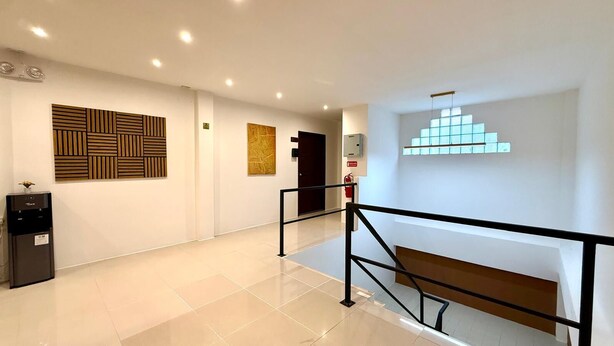 A modern interior with a water dispenser, a staircase, and a wall with geometric patterns. - Deluxe Double Room with Sea View Balcony (Tambon Patong)