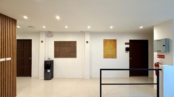 A modern interior with a reception desk, a fire extinguisher, and a door with a number sign.