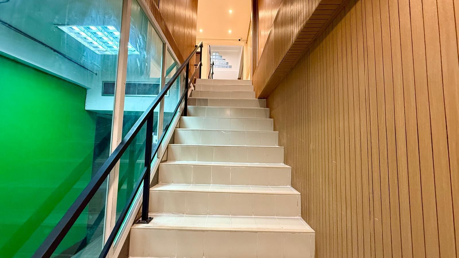 A staircase with a glass railing and wooden paneling on the walls.
