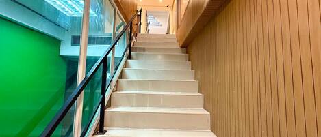 A staircase with a glass railing and wooden paneling on the walls.