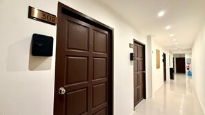 A hotel hallway with a brown door marked '302', a fire extinguisher, and a clean, shiny floor. - Deluxe Double Room with Sea View Balcony (Tambon Patong)