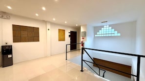 A modern interior with a water dispenser, a staircase, and a wall with geometric patterns. - Patong Beachfront Deluxe Room Sea View (Tambon Patong)