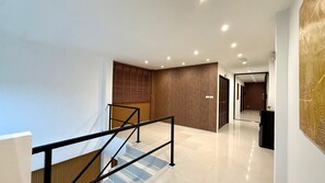 A modern interior with a staircase, a wooden panel wall, and a hallway leading to another room. - Patong Beachfront Superior Room (Tambon Patong)