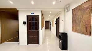 A hotel hallway with a wooden door, a water dispenser, and a patterned wall. - Patong Beachfront Superior Room (Tambon Patong)