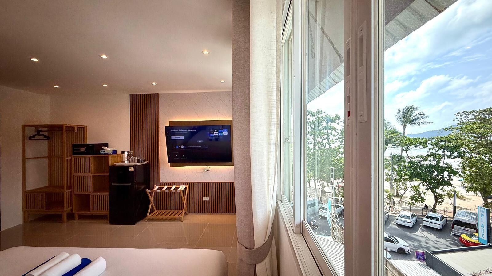 Una camera d'albergo con un letto, una scrivania con un computer, una televisione e vista sulla strada.