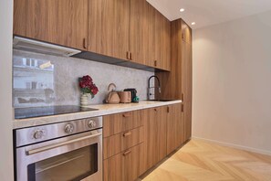 A modern kitchen with wooden cabinets, stainless steel appliances, and a marble countertop. - Elegant Apartment AC St Germain Luxembourg Park (Paris)