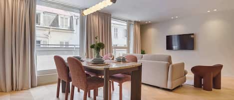 A modern dining area with a round table, chairs, and a hanging light fixture.
