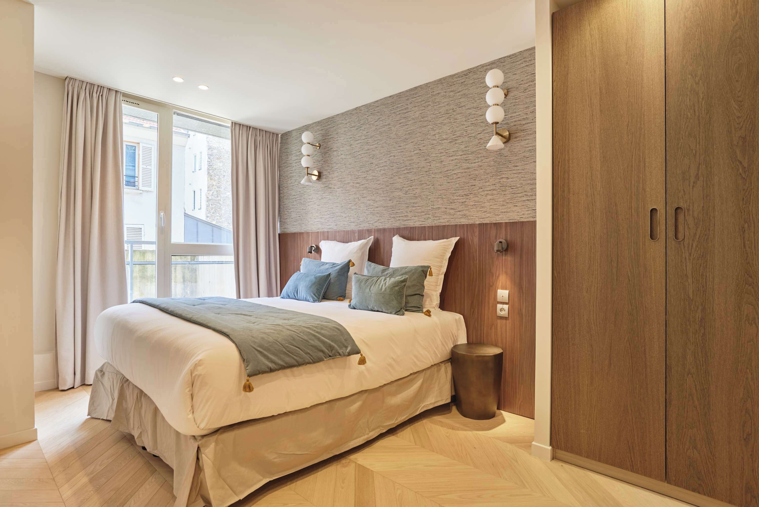 Ein modernes Schlafzimmer mit einem großen Bett, einem Holzkopfende und Blick ins Freie.