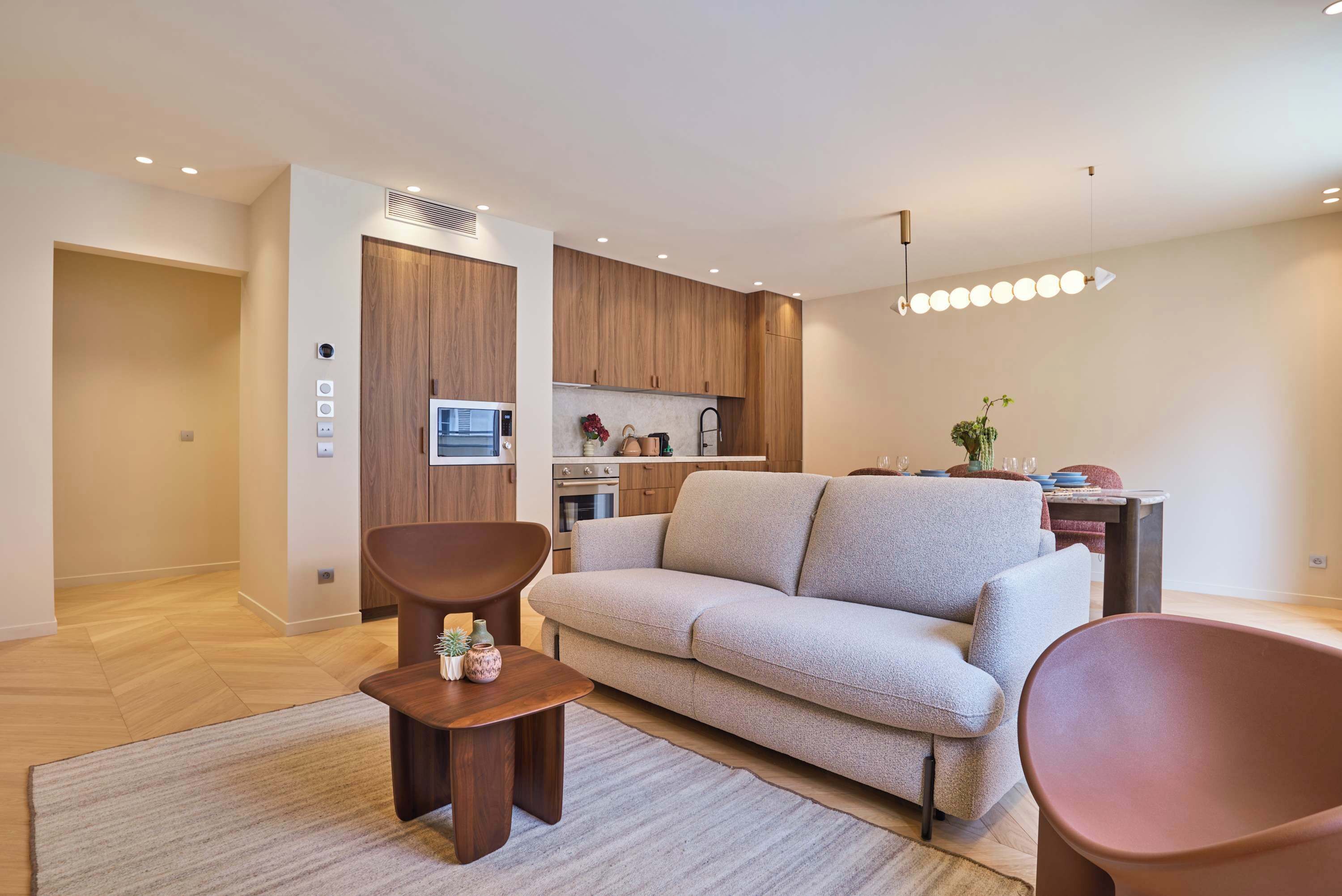 Un salon moderne comprenant un canapé, une table basse et un coin repas avec une table et des chaises.