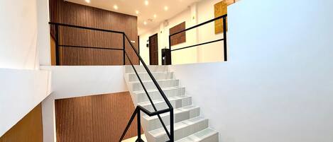 A staircase with a modern design, featuring a black metal railing and wooden paneling on the walls.