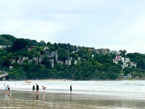 A coastal area with buildings on a hillside and people on the beach. - Patong Superior Beachfront Double Room (Tambon Patong)