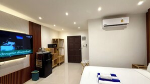 Een hotelkamer met een bed, een televisie, een minibar, een kledingkast en een airconditioning.
