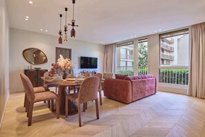 Ein stilvolles Wohnzimmer mit Essbereich, einer Couch und einem Fernseher.