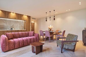 Ein modernes Wohnzimmer mit einem Ecksofa, einem Holztisch und einem Essbereich mit rundem Tisch und Stühlen.