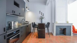 Een moderne keuken met donkere kastjes, een centraal eiland en een eethoek met een open haard.