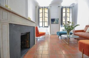 A living room with a fireplace, two windows, a sofa, and a coffee table. - Elegant, air-conditioned apartment in the heart of Aix • 2 minutes from City Hall (Aix-en-Provence)