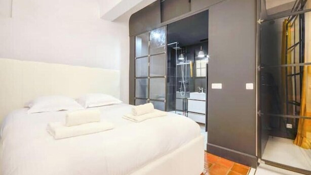 Een hotelkamer met een bed, een badkamer met een glazen deur en een douche.