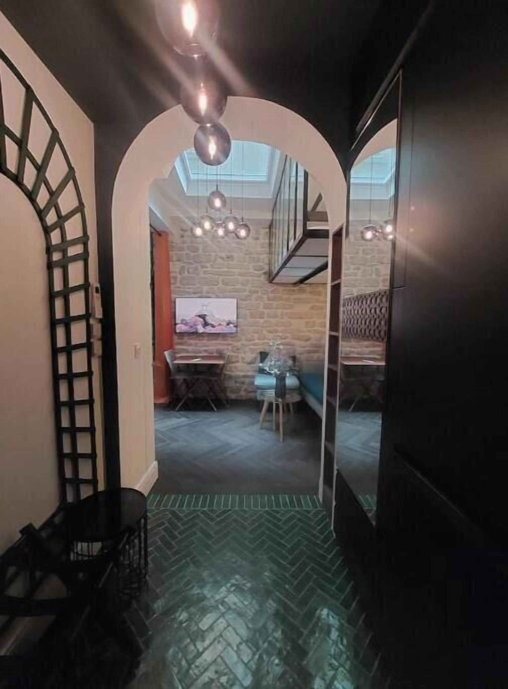 Un pasillo estrecho con un patrón de suelo en espiga, que conduce a un comedor con una mesa y sillas, y una escalera.