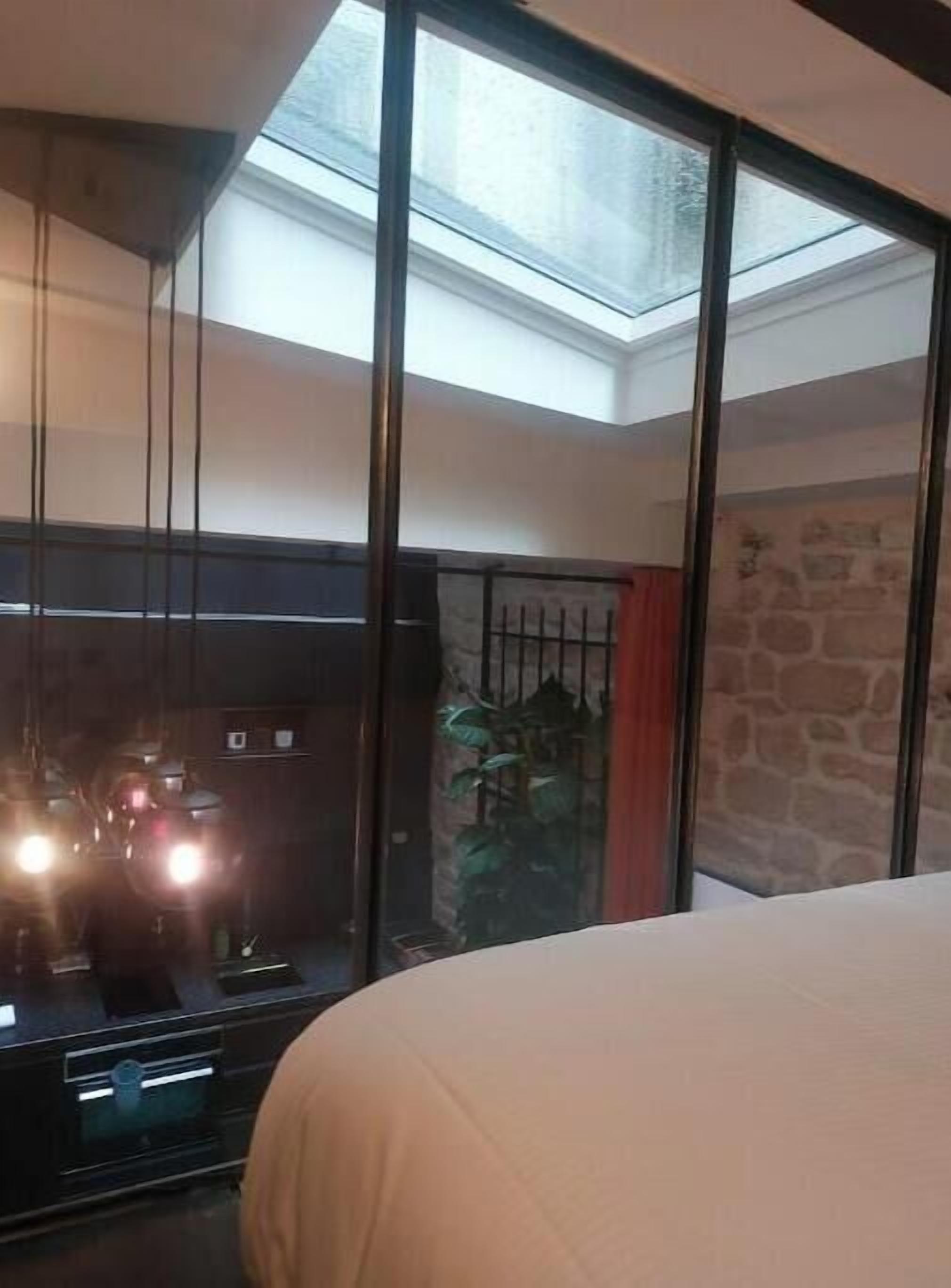 A room with a large window, a bed, and a stone wall.