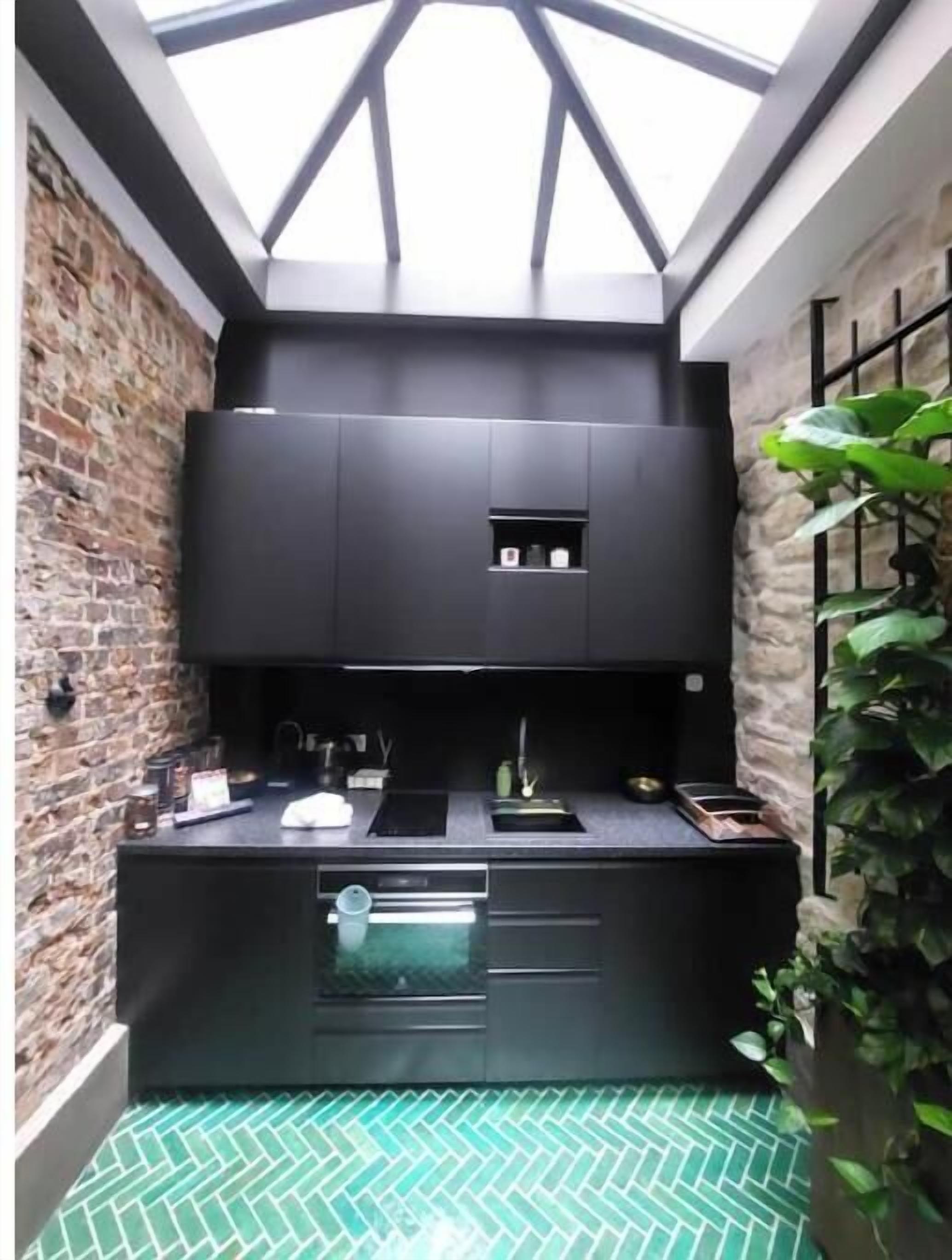 A compact kitchen with a skylight, a brick wall, and a green patterned floor.