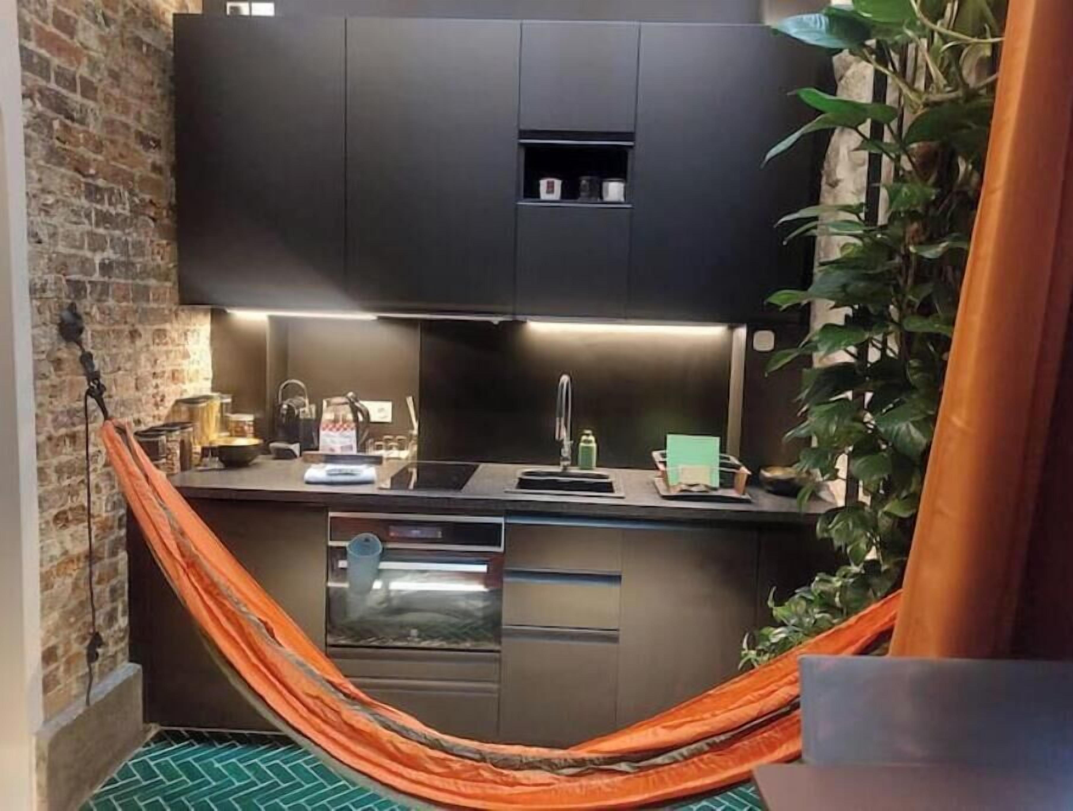 A kitchen with modern appliances, a hanging hammock, and a brick wall.
