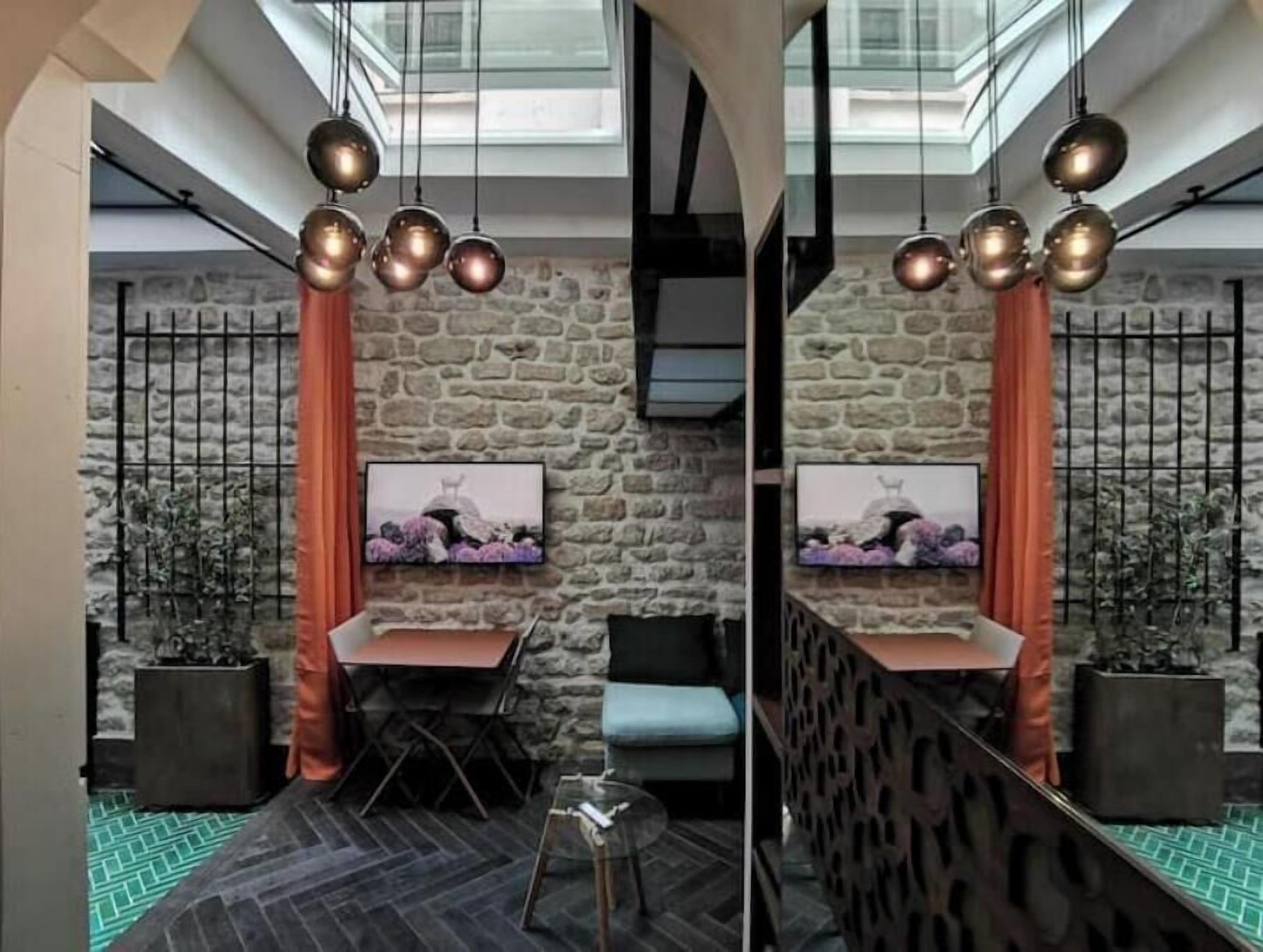 A modern interior with a stone wall, a dining area with a table and chairs, and a hanging light fixture.