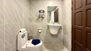 Een badkamer met toilet, wastafel, spiegel en douche.