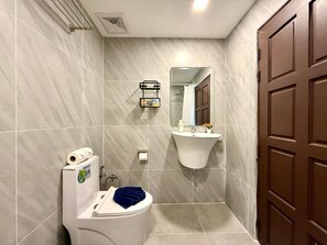 A bathroom with a toilet, sink, mirror, and shower. - Beachfront Deluxe Room with Sea View Balcony (Tambon Patong)