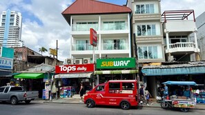 A street scene with a red van, a Tops daily store, and a Subway restaurant. - Beachfront Deluxe Room with Sea View Balcony (Tambon Patong)