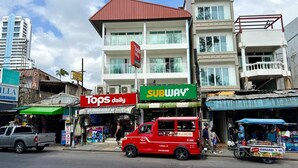 A street scene with a red van, a Tops daily store, and a Subway restaurant. - Deluxe Beachfront Room, Balcony & Sea View (Tambon Patong)