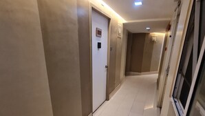A hotel corridor with a tiled floor, a door with a sign, and a window on the right.
