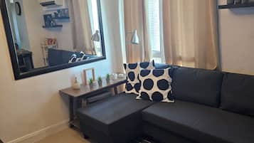 A modern living room with a sectional sofa, a large mirror, and a ceiling light fixture.