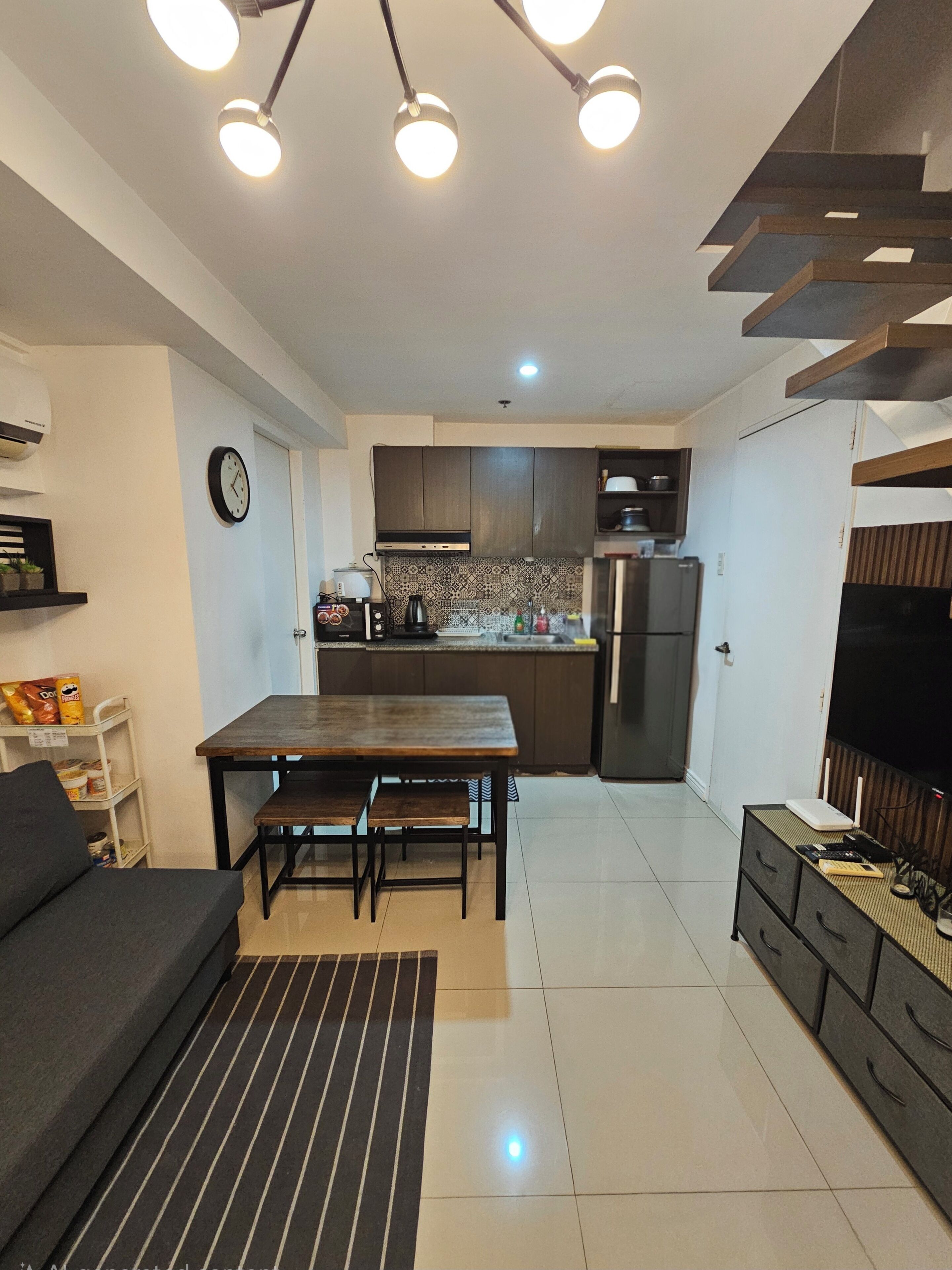 Una cocina compacta con comedor, un sofá y un mueble para televisión.