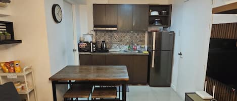Una cocina compacta con comedor, un sofá y un mueble para televisión.