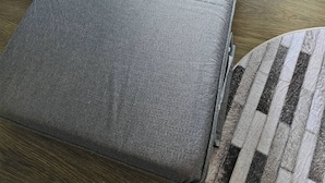 Una stanza con un letto singolo, un comò in legno e un cestino.