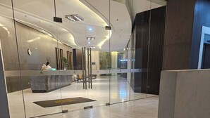 Una hall moderna con una reception, divisori in vetro e un pavimento piastrellato pulito.