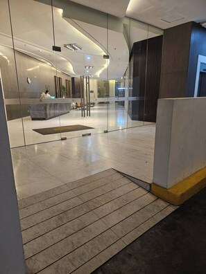 Eine moderne Lobby mit Empfangstresen, Glastrennwänden und einem hellen, gefliesten Boden.