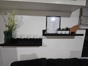 Ein Wohnzimmer mit einer schwarzen Couch, einem Regal mit Dekoration und einem gerahmten Bild.